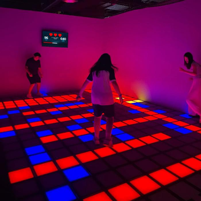 Players moving across red and blue illuminated floor tiles